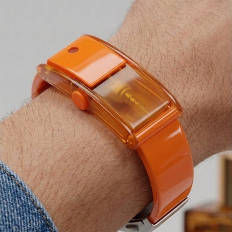 Man wearing Baswick orange refillable perfume bracelet on wrist, close-up view.