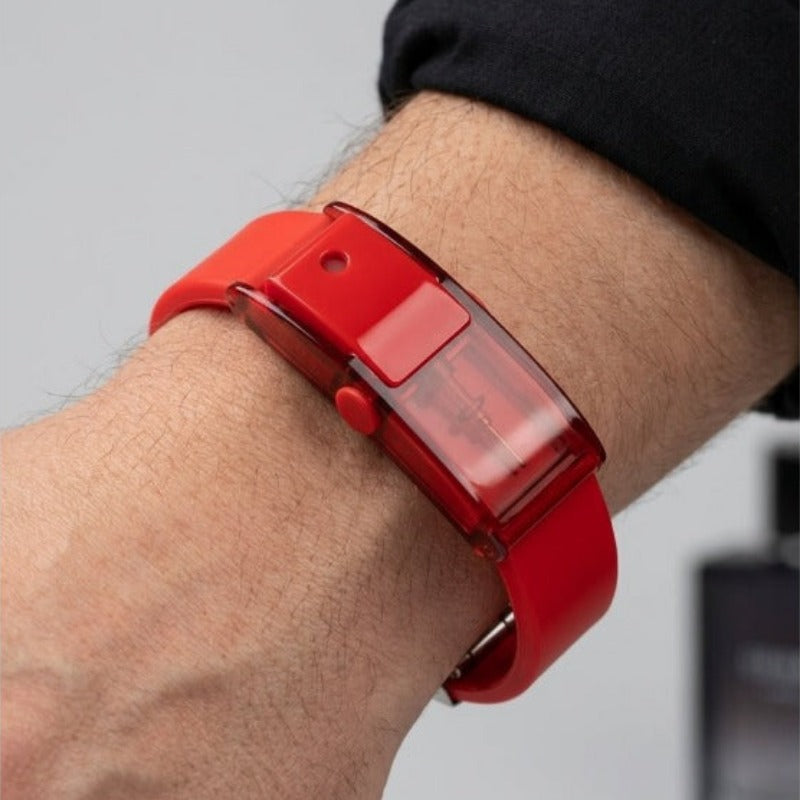 Man wearing Baswick red refillable perfume bracelet on wrist, close-up with perfume bottle in background.